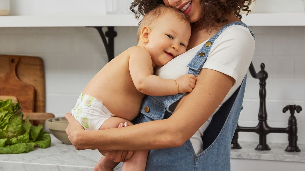 mom in overalls holds baby in diaper